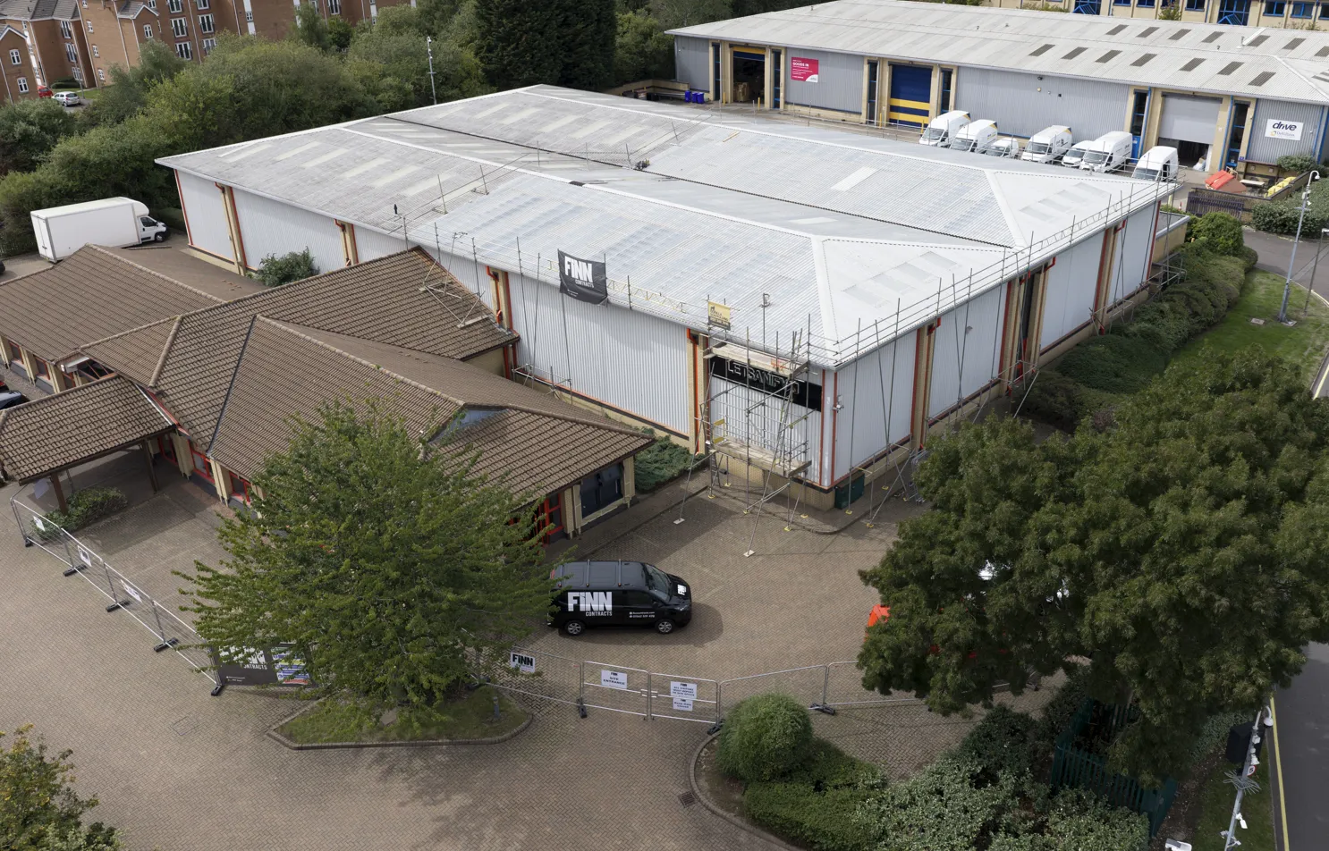 Aerial view of a scaffolded industrial building with a Finn Contracts van outside